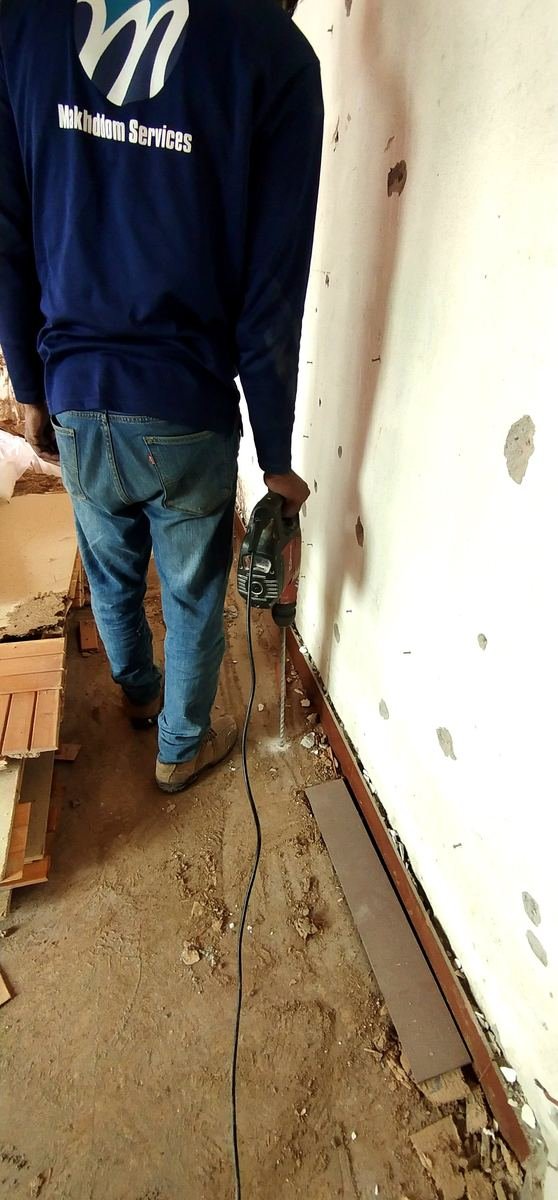 Makhdoom Services technician applying termite chemical barrier along a wall