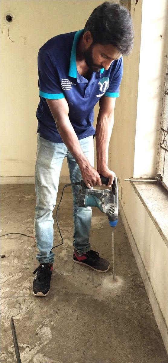 Makhdoom Services technician drilling floor for termite treatment