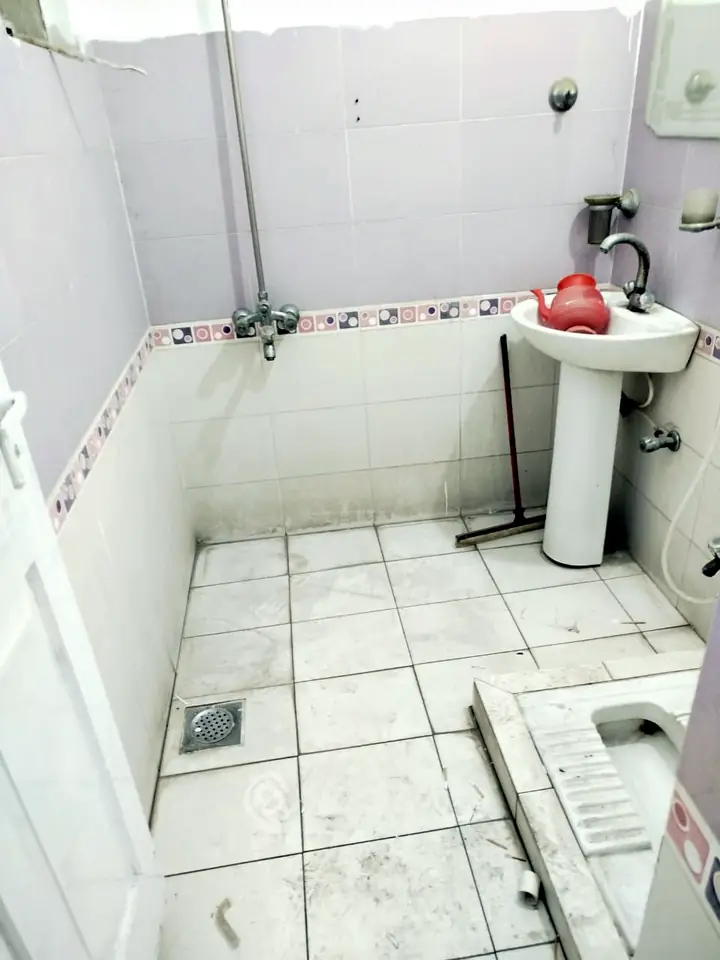 Washroom in a Lahore home before deep cleaning: stained floor tiles, dirty drain and clutter